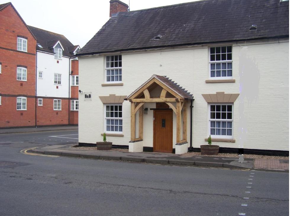 een wit gebouw met een houten deur op een straat bij Bridge House in Henley in Arden