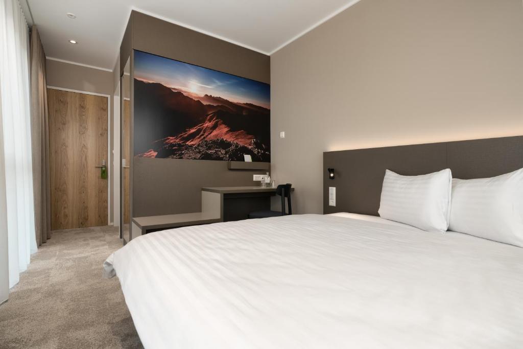 a bedroom with a white bed and a painting on the wall at b-smart motel Schaan in Schaan