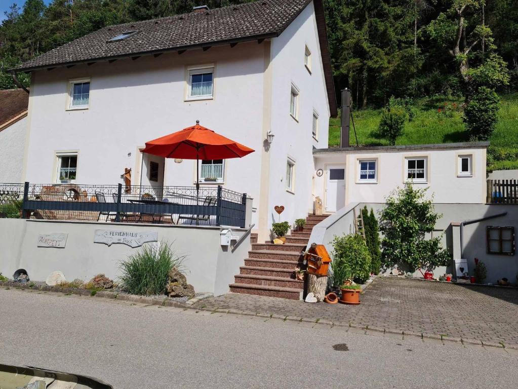 een wit huis met een rode paraplu ervoor bij Ferienhaus am Bach in Riedenburg