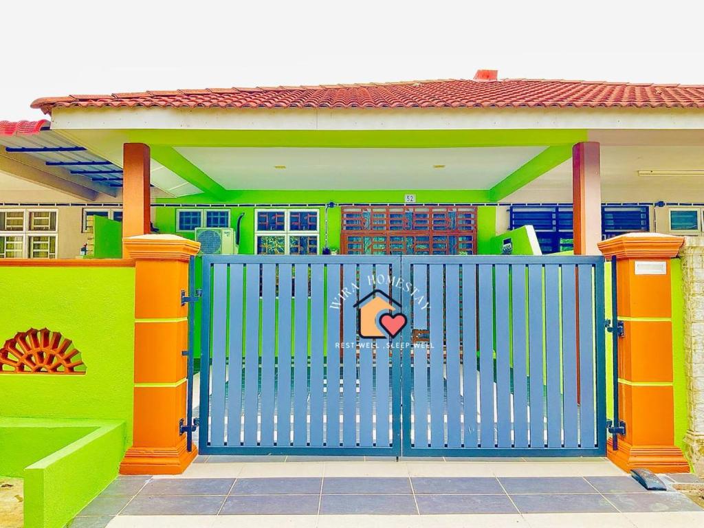 a blue gate in front of a colorful house at WIRA HOMESTAY KUANTAN in Kuantan
