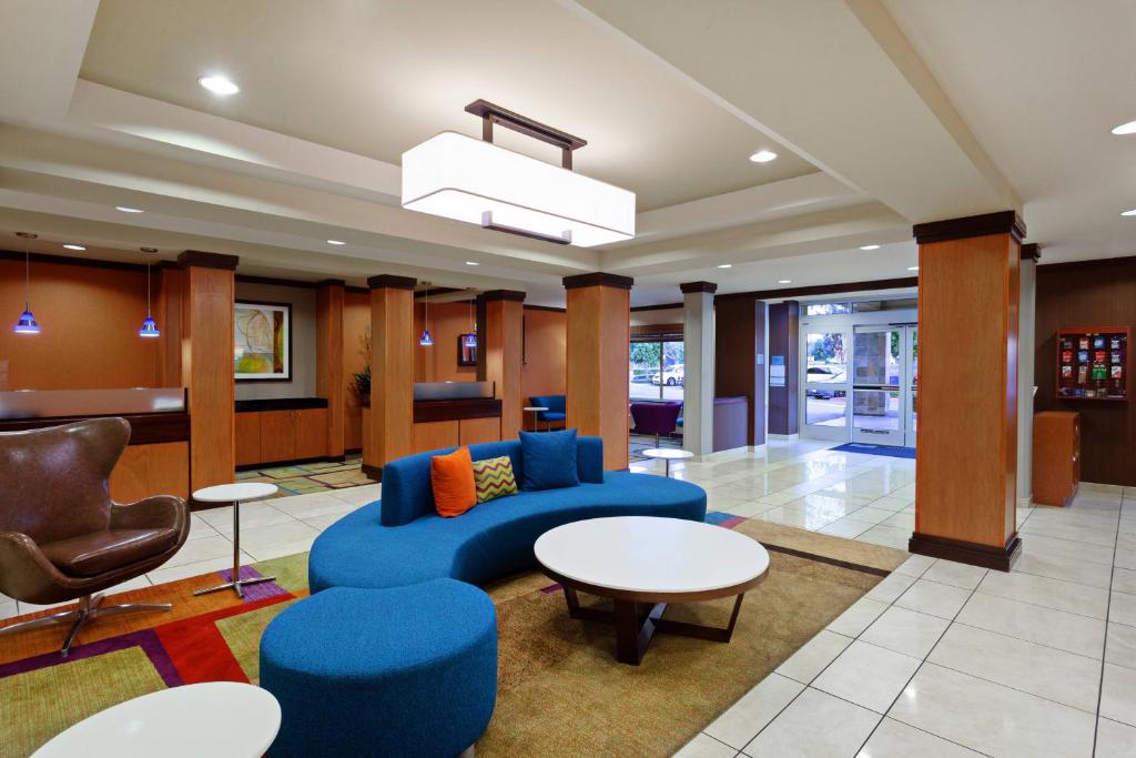 vestíbulo con sofá azul, sillas y mesas en Fairfield Inn & Suites - Los Angeles West Covina, en West Covina