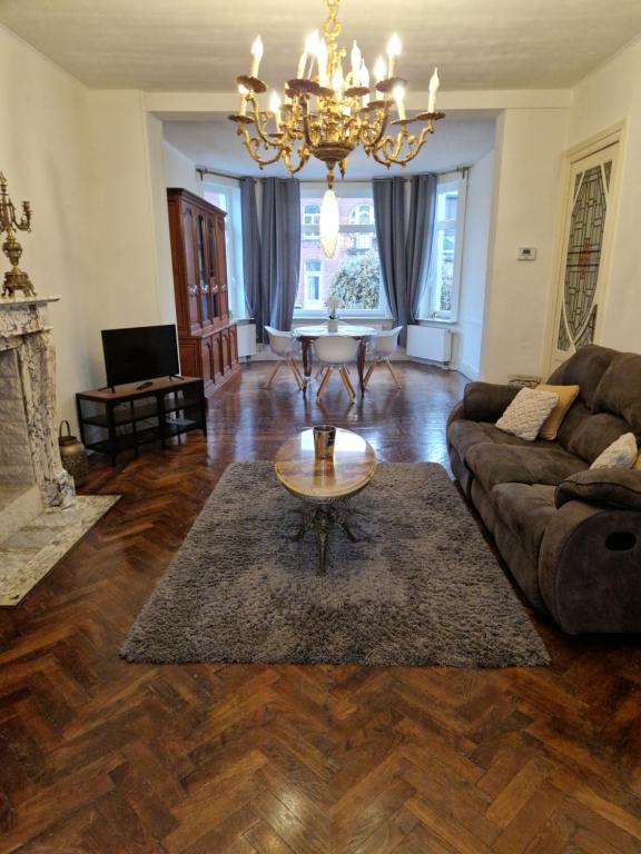 a living room with a couch and a chandelier at Gîte de charme dans une maison bourgeoise in Frameries