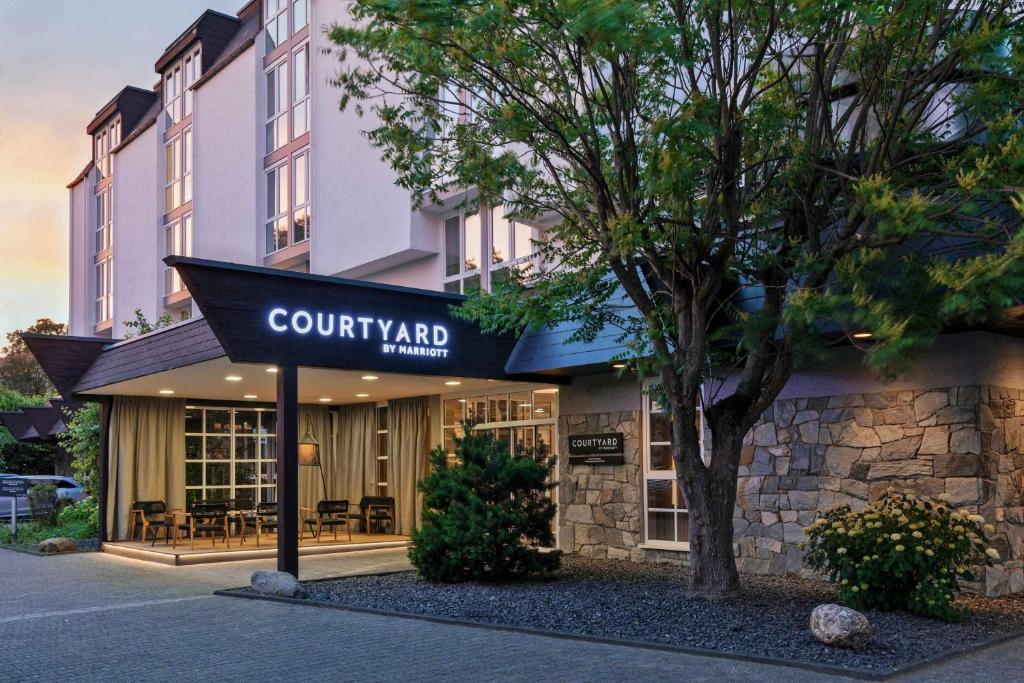 un bâtiment avec un panneau indiquant l'hôtel avec cour dans l'établissement Courtyard by Marriott Wiesbaden-Nordenstadt, à Wiesbaden