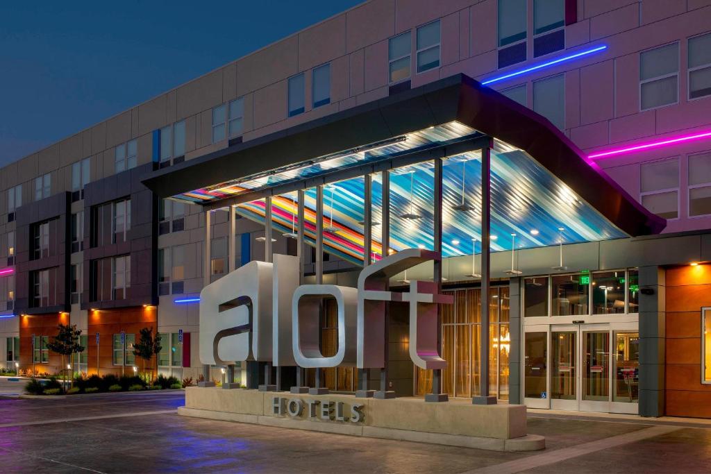 un hôtel avec un panneau devant un bâtiment dans l'établissement Aloft Dallas DFW Airport Grapevine, à Coppell