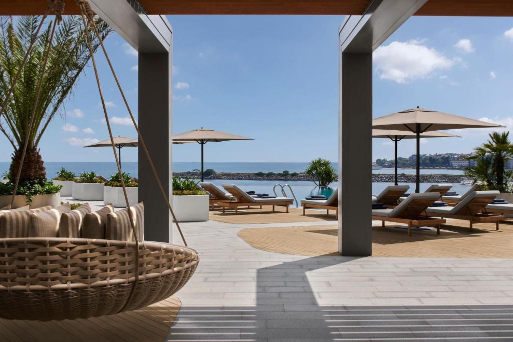 un patio con sillas, sombrillas y agua en JW Marriott Hotel Istanbul Marmara Sea, en Estambul
