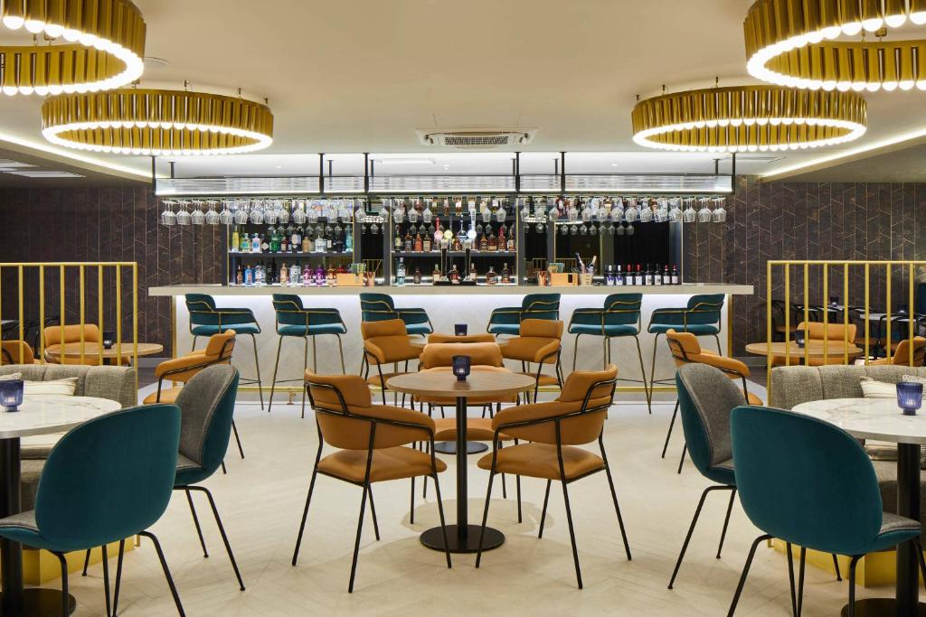 海斯的住宿－Courtyard by Marriott London Heathrow Airport，一间带桌椅的餐厅和一间酒吧
