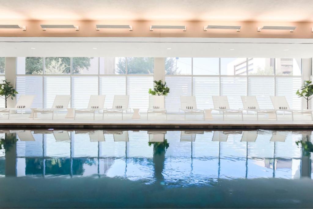 una piscina con sillas blancas en un edificio en Residence Inn by Marriott Dallas Downtown en Dallas