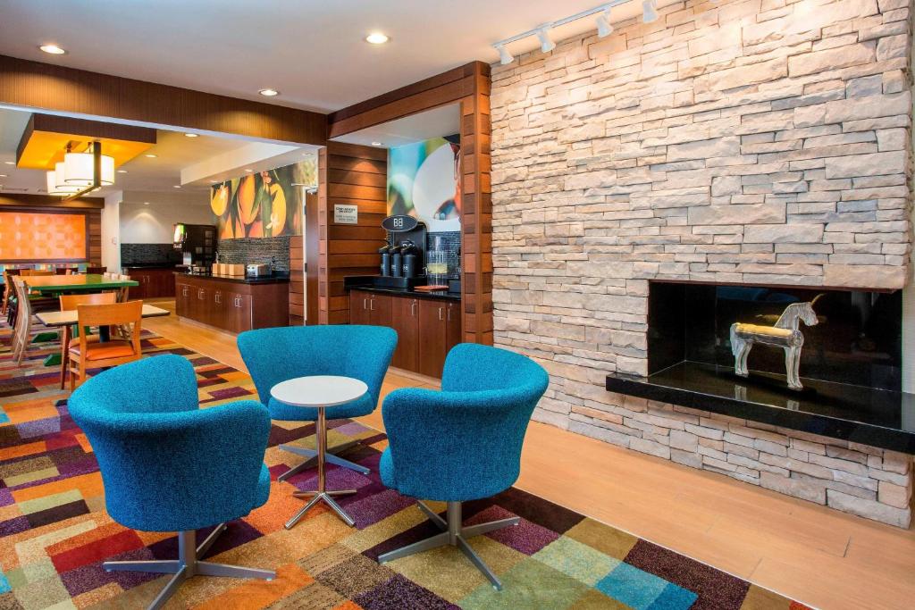 a lobby with blue chairs and a fireplace at Fairfield Inn & Suites Ashland in Ashland