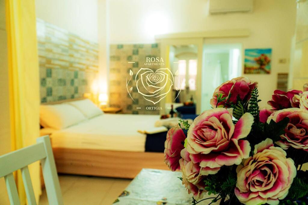 a room with a bed and a table with flowers at Casa Rosa Apartments Ortgia in Siracusa