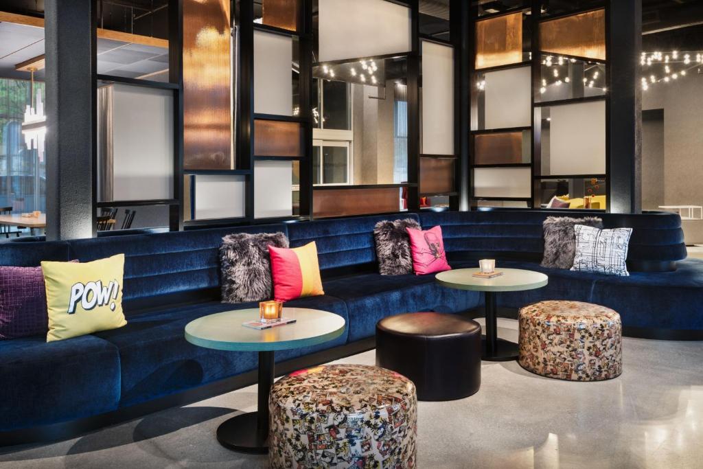 a blue couch with two tables and two stools at Aloft Lawrenceville Sugarloaf in Lawrenceville