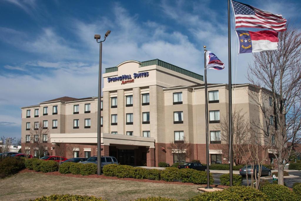 dos banderas están volando frente a un hotel en SpringHill Suites by Marriott Greensboro en Greensboro