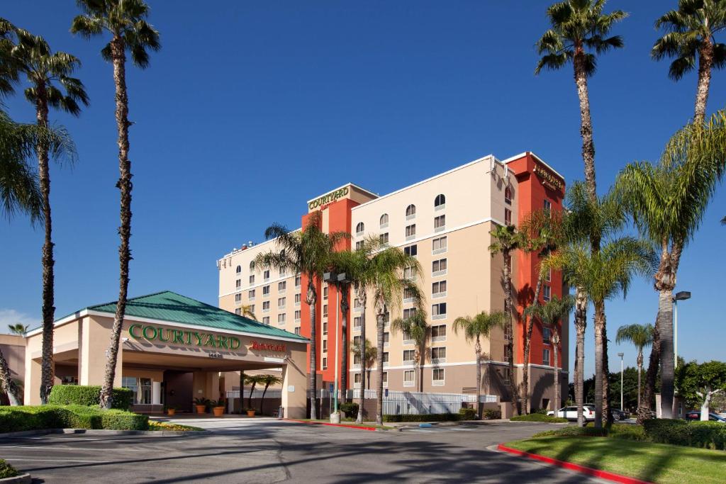 a building with palm trees in front of a street at Courtyard by Marriott Baldwin Park in Baldwin Park