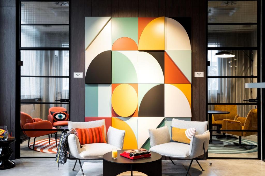 a lobby with chairs and a colorful wall at Moxy Dortmund City in Dortmund