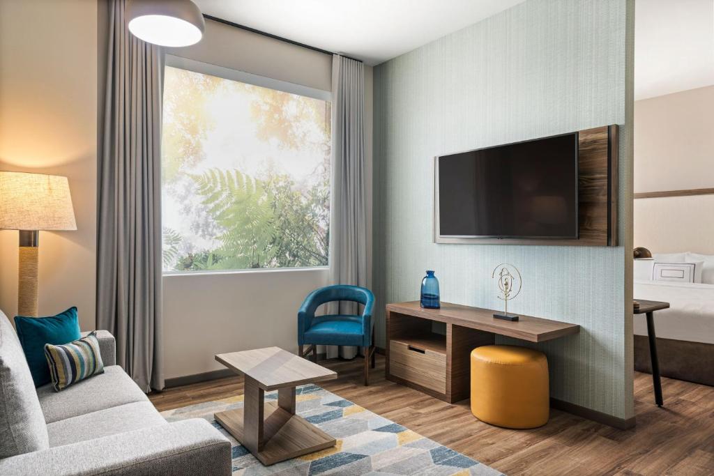 a hotel room with a couch and a desk and a tv at Fairfield by Marriott San Jose Airport Alajuela in Alajuela City