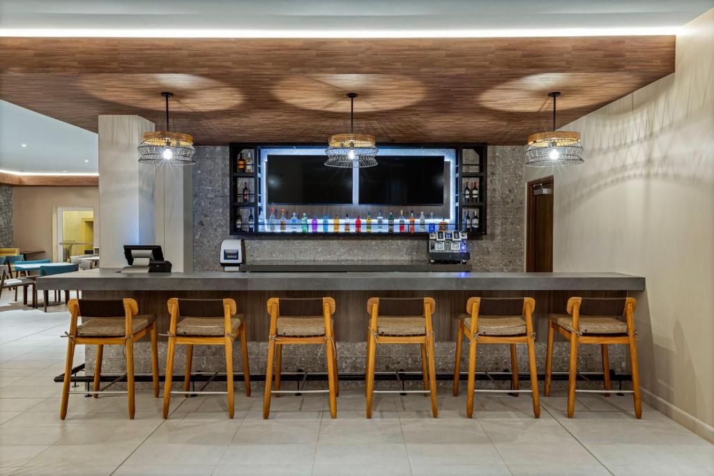 a bar in a lobby with chairs and a tv at Fairfield by Marriott San Jose Airport Alajuela in Alajuela City