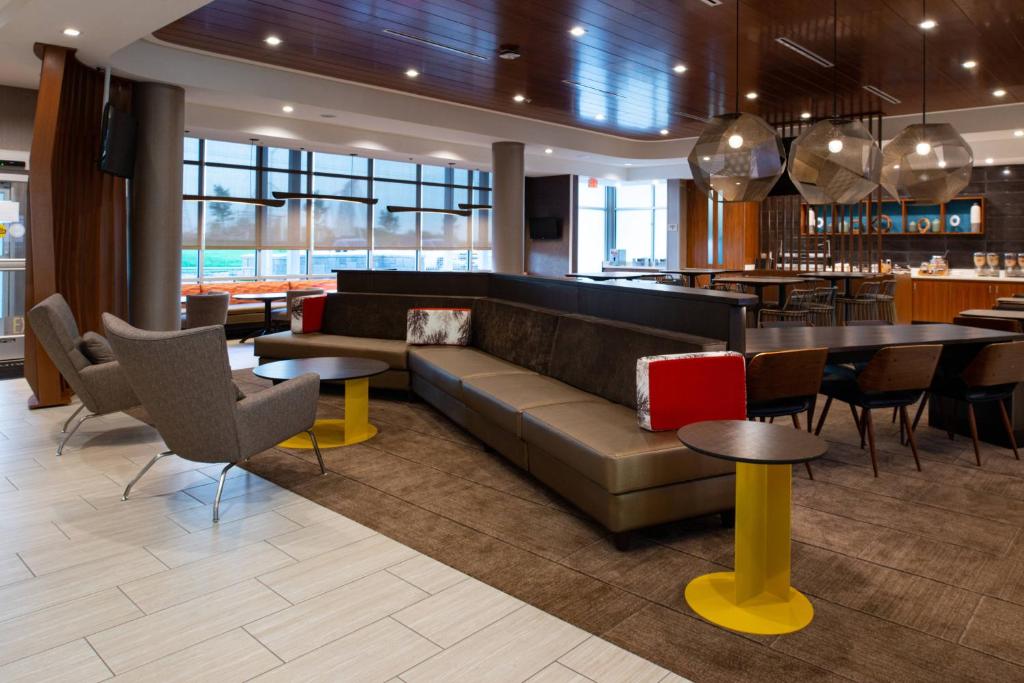 a lobby with a couch and tables and a bar at SpringHill Suites by Marriott Kansas City Northeast in Kansas City