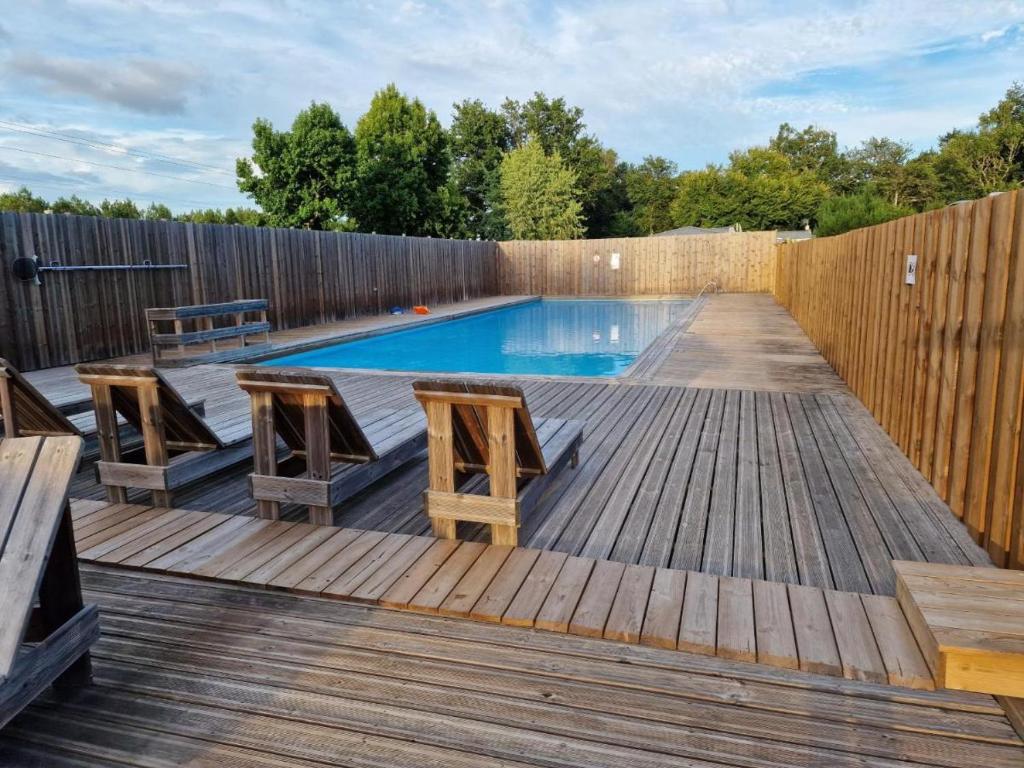 a swimming pool on a wooden deck with a wooden fence at Mobil home 6 personnes Forêt des landes in Mimizan