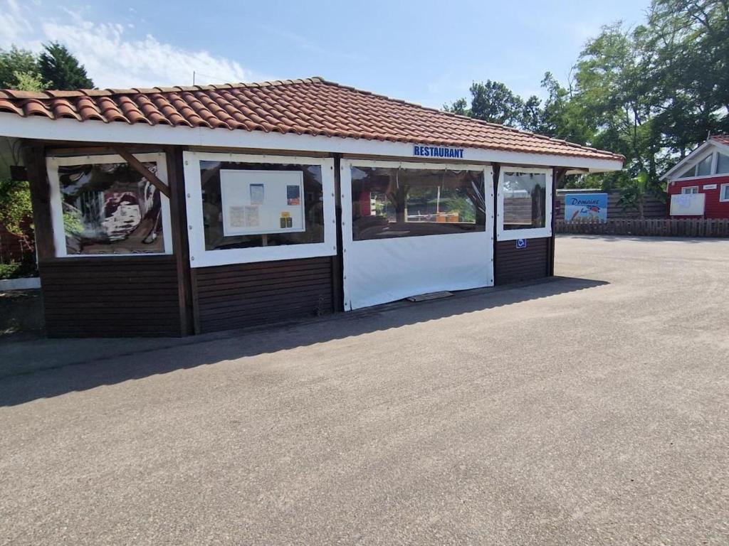 a small building with a white door and windows at Mobil home 6 personnes Forêt des landes in Mimizan