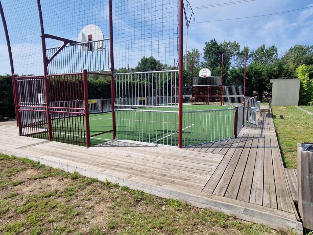 a basketball hoop on a wooden deck with a tennis court at Mobil home 6 personnes Forêt des landes in Mimizan