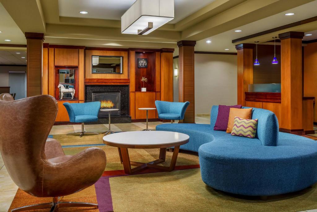 uma sala de estar com um sofá, uma mesa e cadeiras em Fairfield by Marriott Peoria East em Peoria