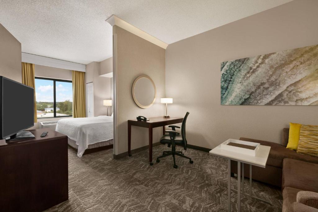 SpringHill Suites Dulles Airport في ستيرلينغ: غرفة في الفندق بها سرير ومكتب وبه جهاز كمبيوتر