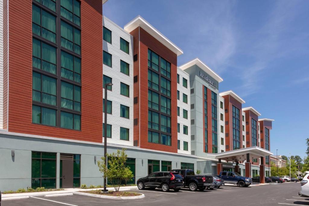 Residence Inn by Marriott Virginia Beach Town Center في فرجينيا بيتش: صف من المباني مع السيارات تقف في موقف للسيارات