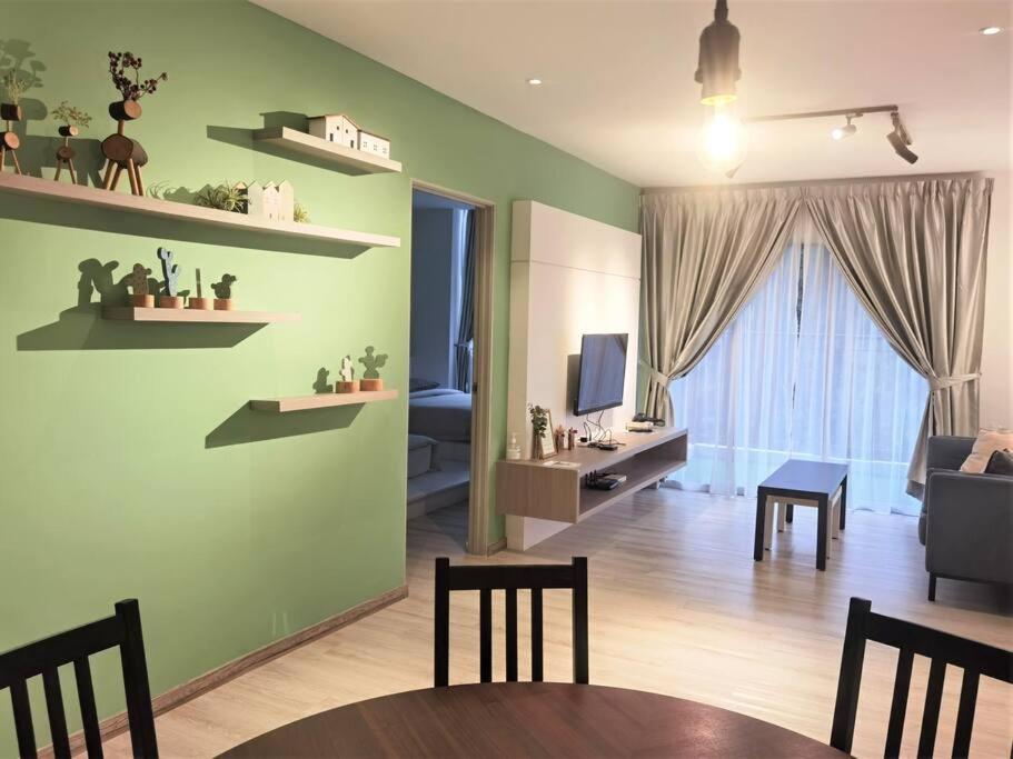 ein Wohnzimmer mit grünen Wänden sowie einem Tisch und Stühlen in der Unterkunft Emerald Avenue Cozy 3R3B Apartment - 329 in Brinchang