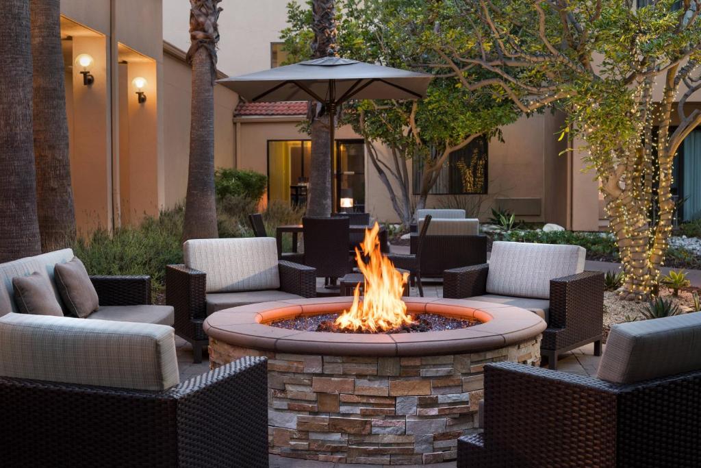 een vuurplaats op een binnenplaats met stoelen en een parasol bij Courtyard Los Angeles Torrance/Palos Verdes in Torrance