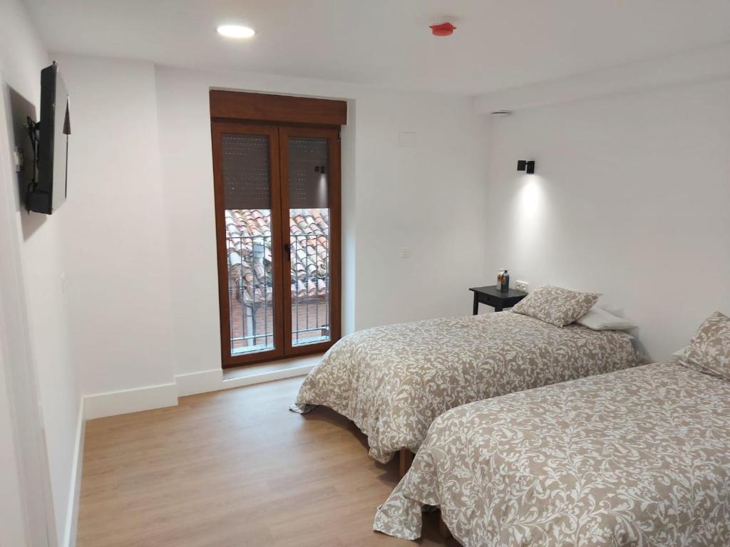 a bedroom with two beds and a window at Hotel - Hostel Atuvera in Santo Domingo de la Calzada