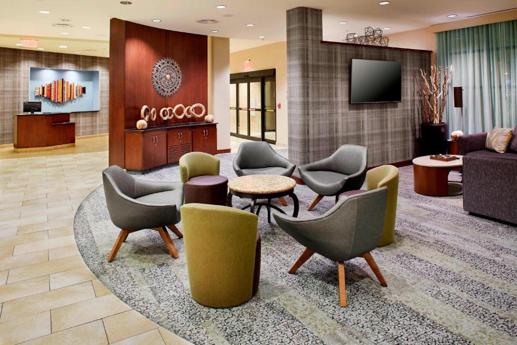 a lobby with chairs and a couch and a tv at Courtyard Hamilton in Hamilton