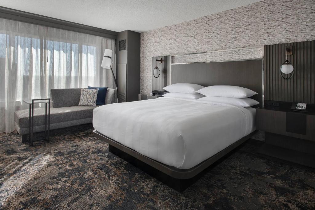 een slaapkamer met een groot wit bed en een bank bij Bridgewater Marriott in Bridgewater