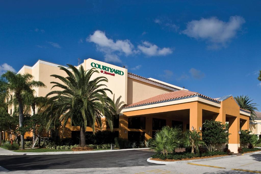 a hotel building with palm trees in front of it at Courtyard by Marriott Boynton Beach in Boynton Beach