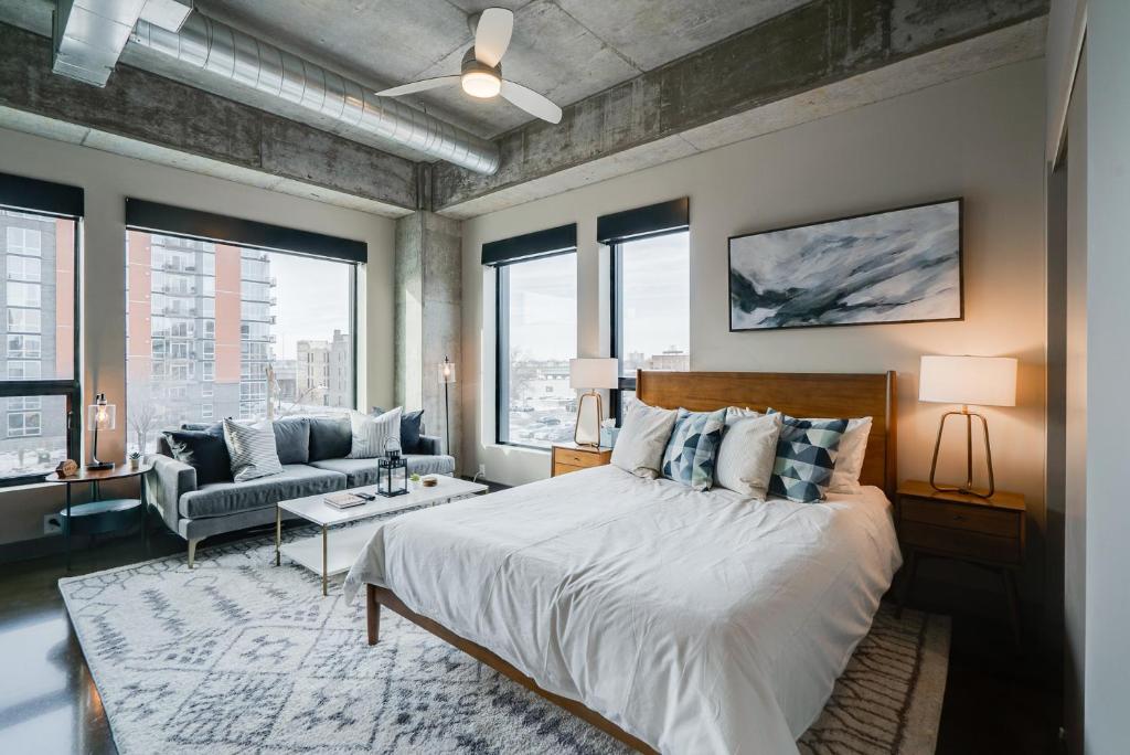 ein Schlafzimmer mit einem Bett, einem Sofa und Fenstern in der Unterkunft Sable 31 - Studio in Minneapolis