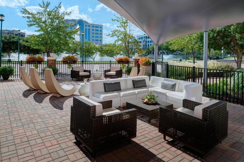 een patio met witte banken, tafels en stoelen bij Newport News Marriott at City Center in Newport News