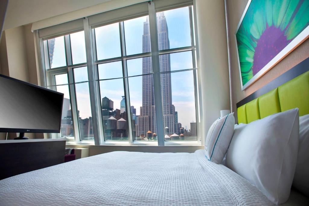 ein Schlafzimmer mit einem Bett und einem großen Fenster in der Unterkunft SpringHill Suites by Marriott New York Midtown Manhattan/Fifth Avenue in New York