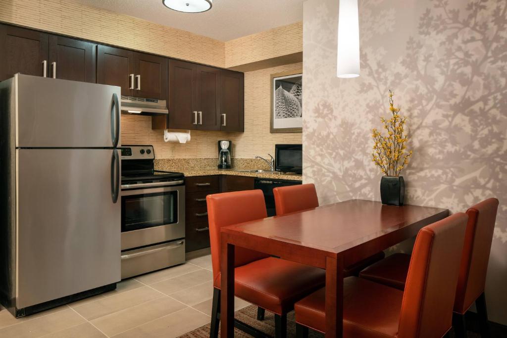 Residence Inn Milpitas Silicon Valley في ميلبيتاس: مطبخ مع طاولة خشبية وثلاجة