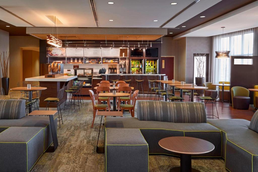 a restaurant with tables and chairs and a bar at Courtyard by Marriott Kingston Highway 401 in Kingston