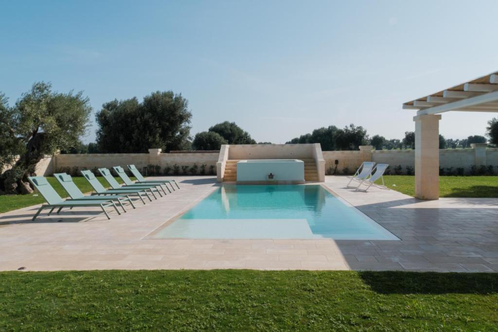 a pool with lawn chairs and a laptop on it at Masseria Egnazia - Epoca Collection in Savelletri di Fasano