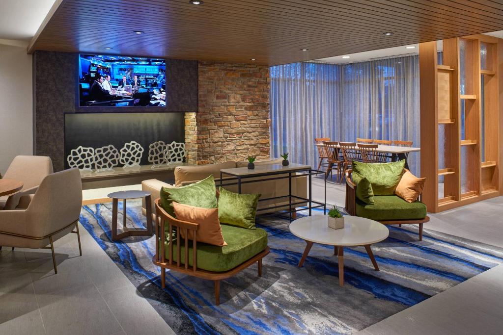 eine Lobby mit Stühlen, Tischen und einem TV in der Unterkunft Fairfield Inn & Suites by Marriott Midland in Midland