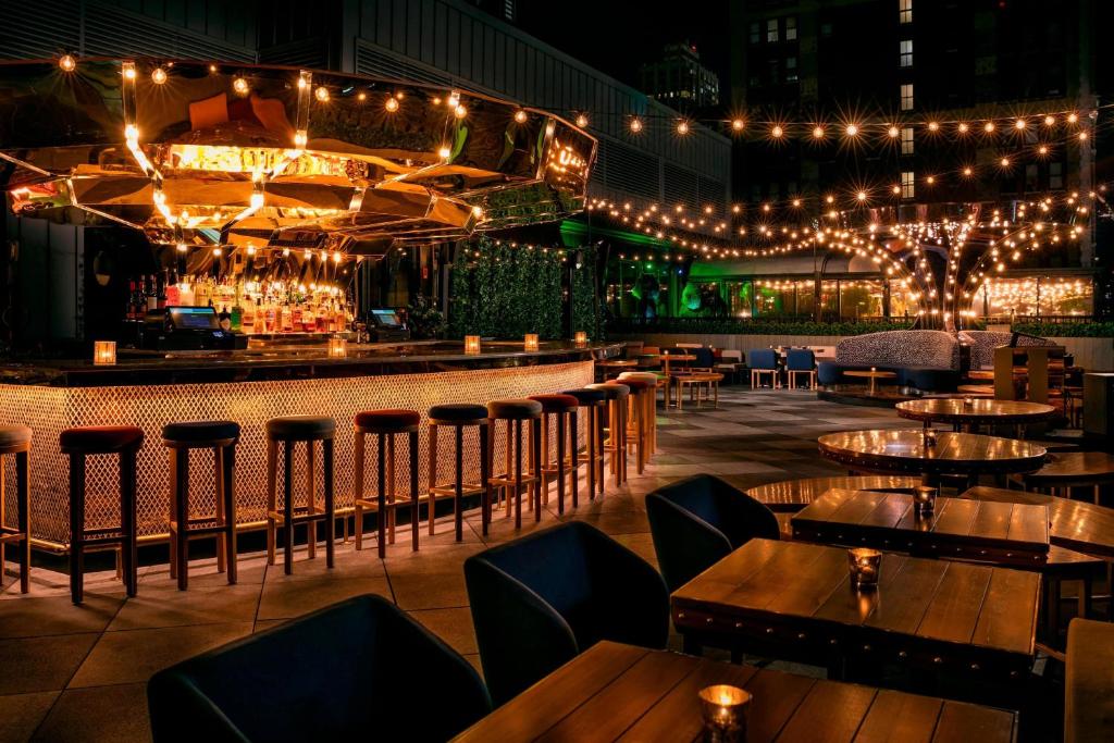 a bar with tables and chairs and lights at MOXY NYC Times Square in New York