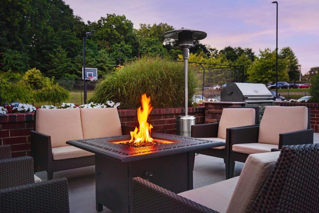 a fire pit on a patio with chairs and a grill at Residence Inn Poughkeepsie in Poughkeepsie