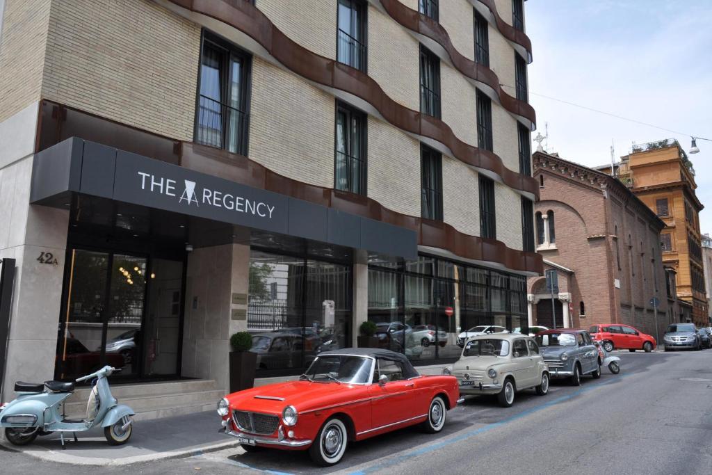 un'auto rossa parcheggiata di fronte a un edificio di The Regency, Rome, a Tribute Portfolio Hotel a Roma