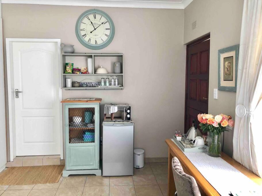 a room with a refrigerator and a clock on the wall at Lavender Lane Cottage in Johannesburg