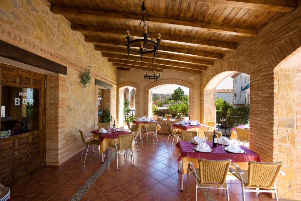 un comedor con mesas, sillas y ventanas en Hostal Las Rumbas, en Nuévalos