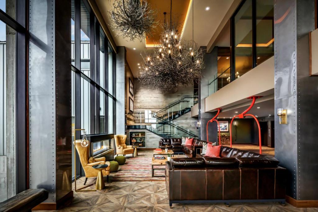 a lobby with a couch and chairs and a chandelier at The Josie Hotel, Autograph Collection in Rossland