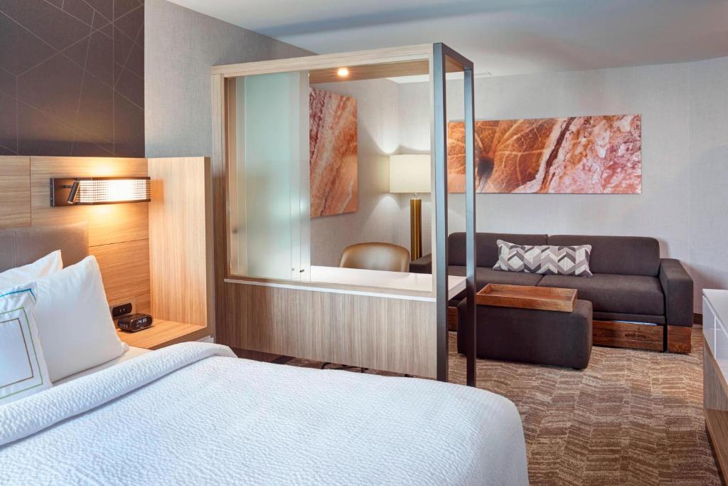 SpringHill Suites by Marriott Grand Rapids West في غراندفيل: غرفه فندقيه بسرير واريكه