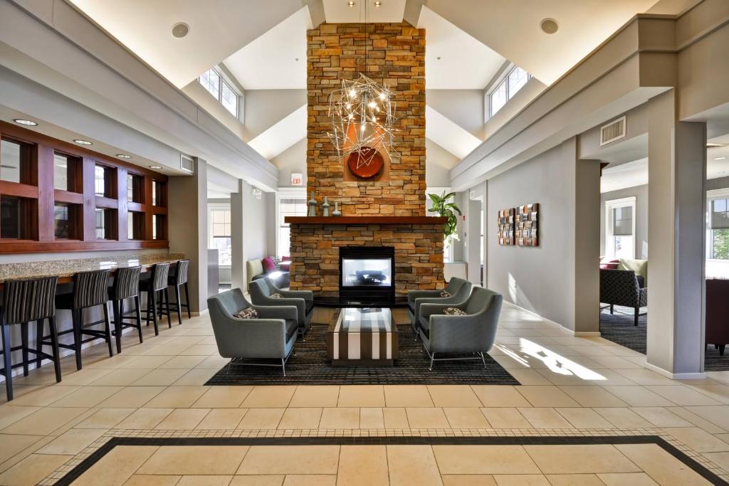a lobby with a fireplace and chairs and a bar at Residence Inn Saint Louis O'Fallon in O'Fallon