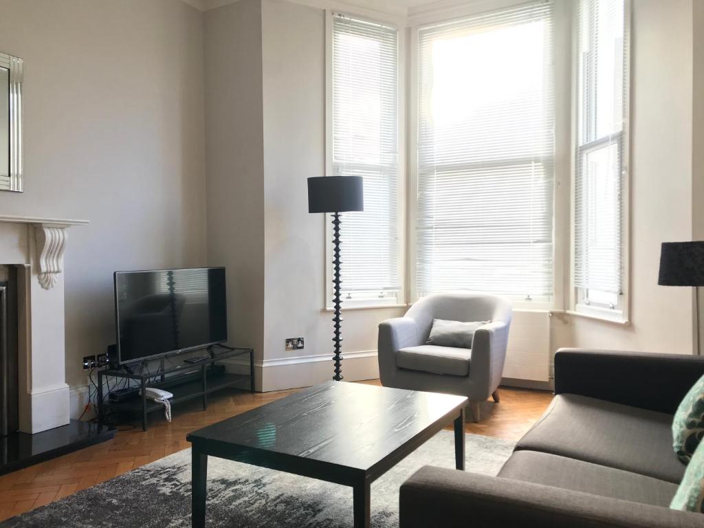 uma sala de estar com um sofá, uma mesa e uma televisão em 25 Ongar Road by Viridian Apartments em Londres