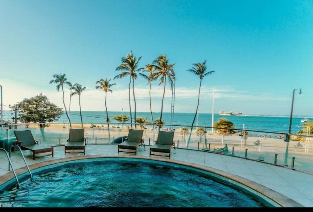 a swimming pool next to a beach with palm trees at Apto Beira Mar 2102 in Fortaleza