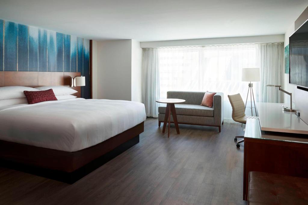 Toronto Marriott City Centre Hotel في تورونتو: غرفه فندقيه بسرير وكرسي وطاولة